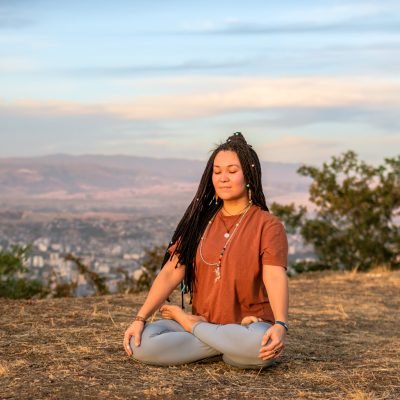 Young woman is sitting in the lotus position and meditating on mountain top. Concept of healthy lifestyle.